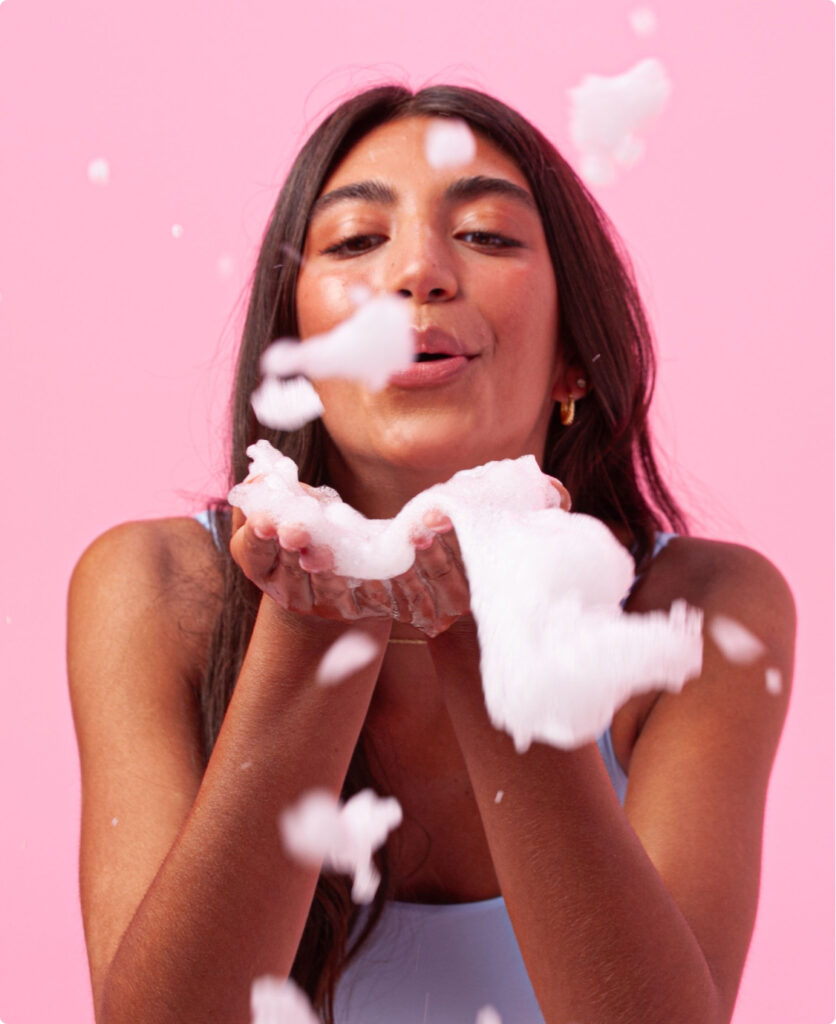 A teen girl blowing Fawn foam cleanser from her hands.